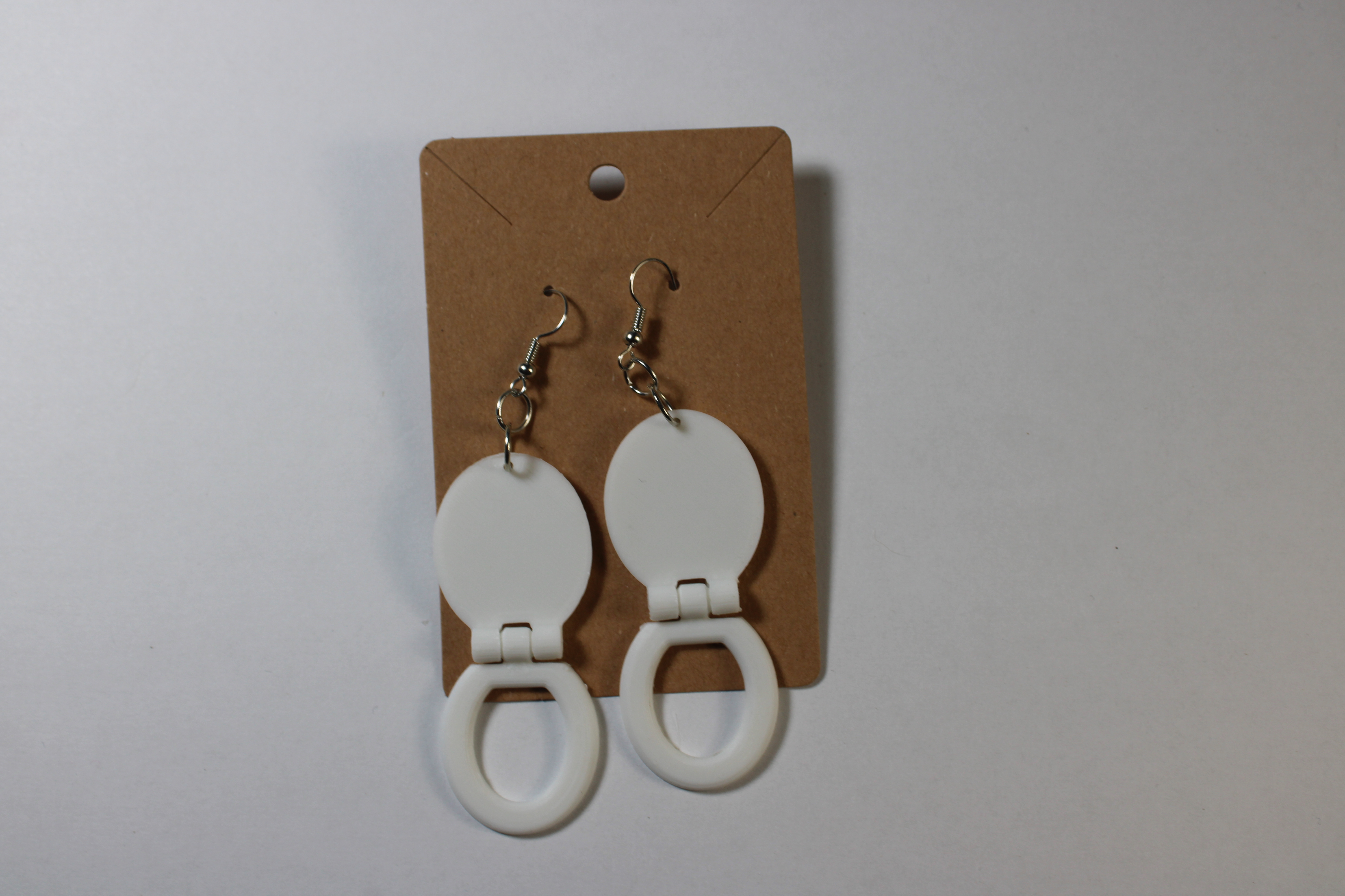 Two White Toilet Seat Earrings on display card