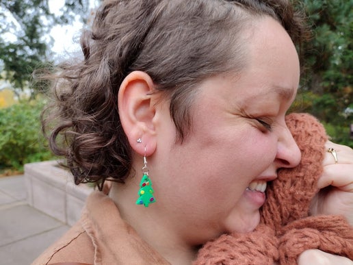 Woman wearing Christmas tree earrings with rainbow colored ornaments