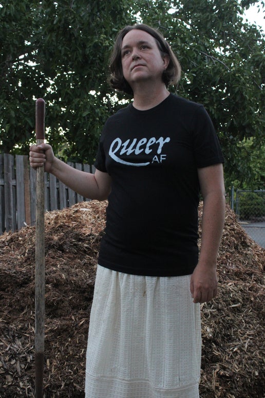 Jaelyn wearing the Queer AF shirt in the garden and holding a shovel