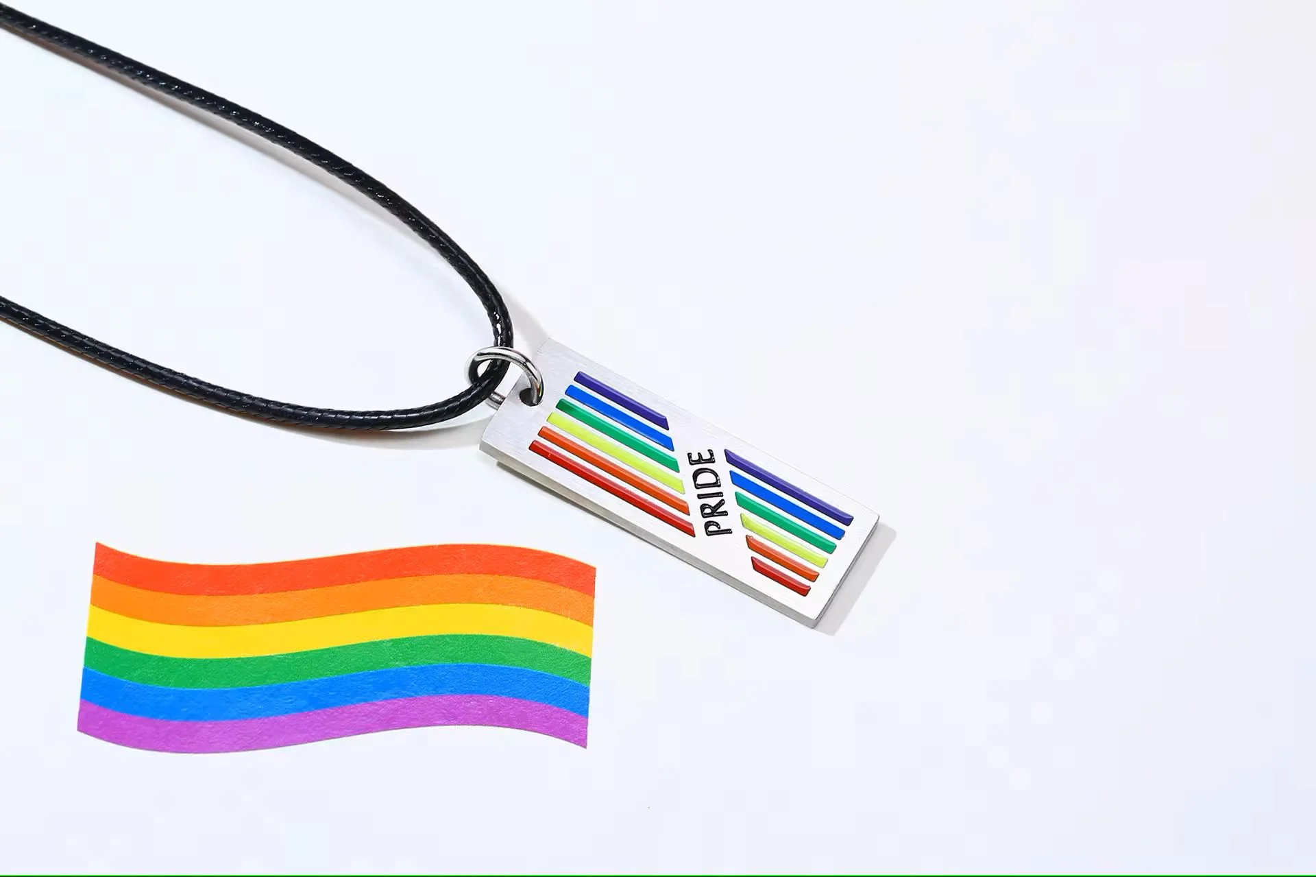  Rainbow Pride Rectangle Pendant with Rope Chain next to rainbow